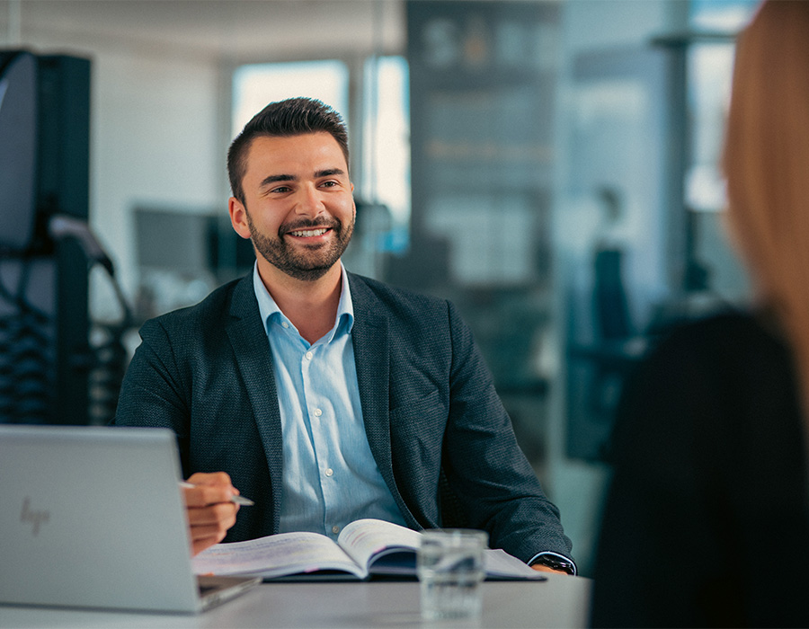 Ein Mitarbeitender im Vertrieb führt ein Gespräch mit einer Kundin im Büro des Unternehmens