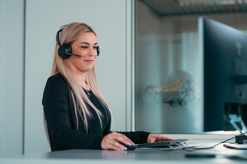 Eine duale Studentin arbeitet mit Headset an ihrem Arbeitsplatz im Büro