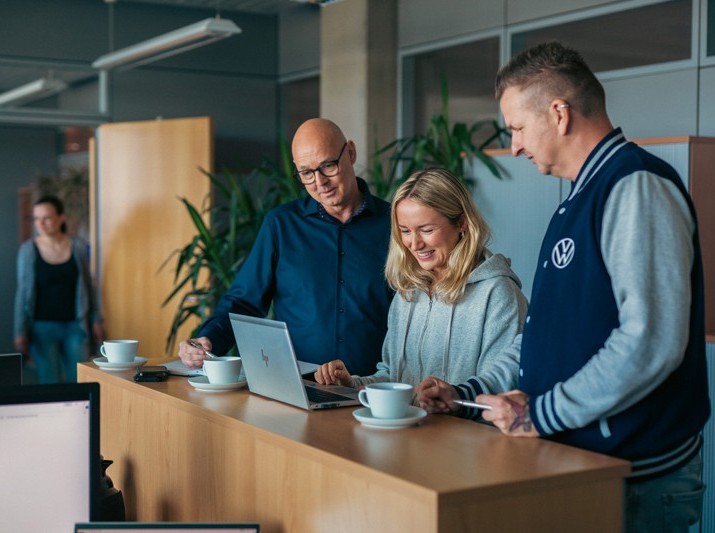 Drei Mitarbeitende besprechen gemeinsam ein Projekt am Laptop im Büro des Unternehmens